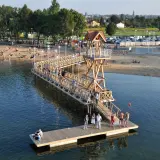 Ludzie odpoczywają na plaży i w wodzie przy drewnianym molo w Pogorii, Dąbrowa Górnicza.
