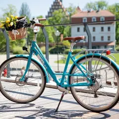 Błękitny rower z koszykiem pełnym żółtych tulipanów. Dowiedz się, jak zamontować koszyk na rower na klik, by cieszyć się wiosennymi przejażdżkami.
