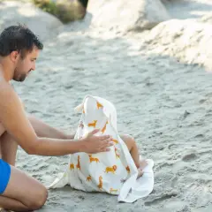 Tata otula dziecko w ręcznik na basen z motywem zwierzątek.