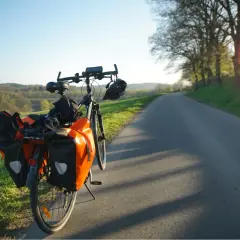 Rower z pomarańczowymi sakwami gotowy do podróży szlakiem rowerowym pomarańczowym. Słoneczny dzień zaprasza do jazdy.