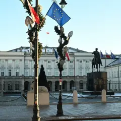 Pałac Prezydencki w Warszawie, z pomnikiem konnym i flagami, w tym flagą UE. To miejsce, gdzie odbywają się ważne wydarzenia, a co to jest kadencja, można poczuć w atmosferze tego miejsca.