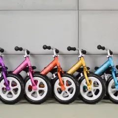 Kolorowe rowerki biegowe ustawione w rzędzie. Idealne na pierwszy rowerek biegowy dla malucha.