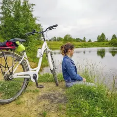 Dziewczyna odpoczywa nad jeziorem po przejażdżce rowerowej po malowniczych trasach rowerowych Gliwice.