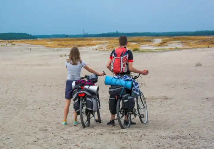 Para rowerzystów z sakwami na rowerach na piaszczystej trasie rowerowej Pustynia Błędowska.