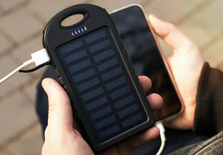 Ręce trzymające powerbank na rower z panelem słonecznym ładujący telefon. Idealny na wycieczki!
