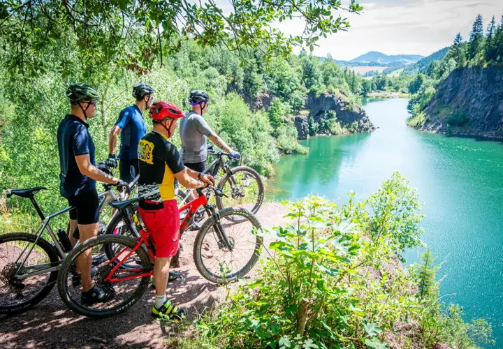 Czterech rowerzystów MTB podziwia malowniczy widok na turkusowe jezioro w Sudetach. Idealne miejsce na rowerową przygodę.