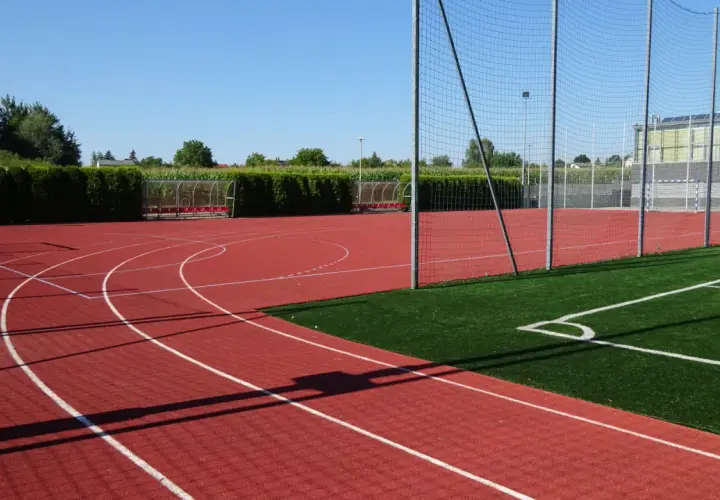 Bieruński ośrodek sportu i rekreacji: bieżnia, boisko ze sztuczną trawą, bramki i zadaszone ławki.