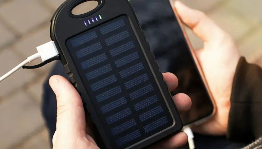 Ręce trzymające powerbank na rower z panelem słonecznym ładujący telefon. Idealny na wycieczki!