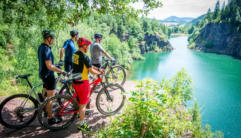 Czterech rowerzystów MTB podziwia malowniczy widok na turkusowe jezioro w Sudetach. Idealne miejsce na rowerową przygodę.
