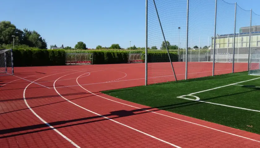 Bieruński ośrodek sportu i rekreacji: bieżnia, boisko ze sztuczną trawą, bramki i zadaszone ławki.