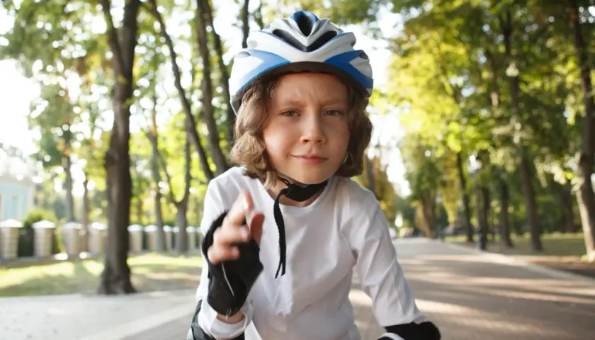 Dziecko w kasku rowerowym na głowie, gotowe do jazdy po alei w parku.
