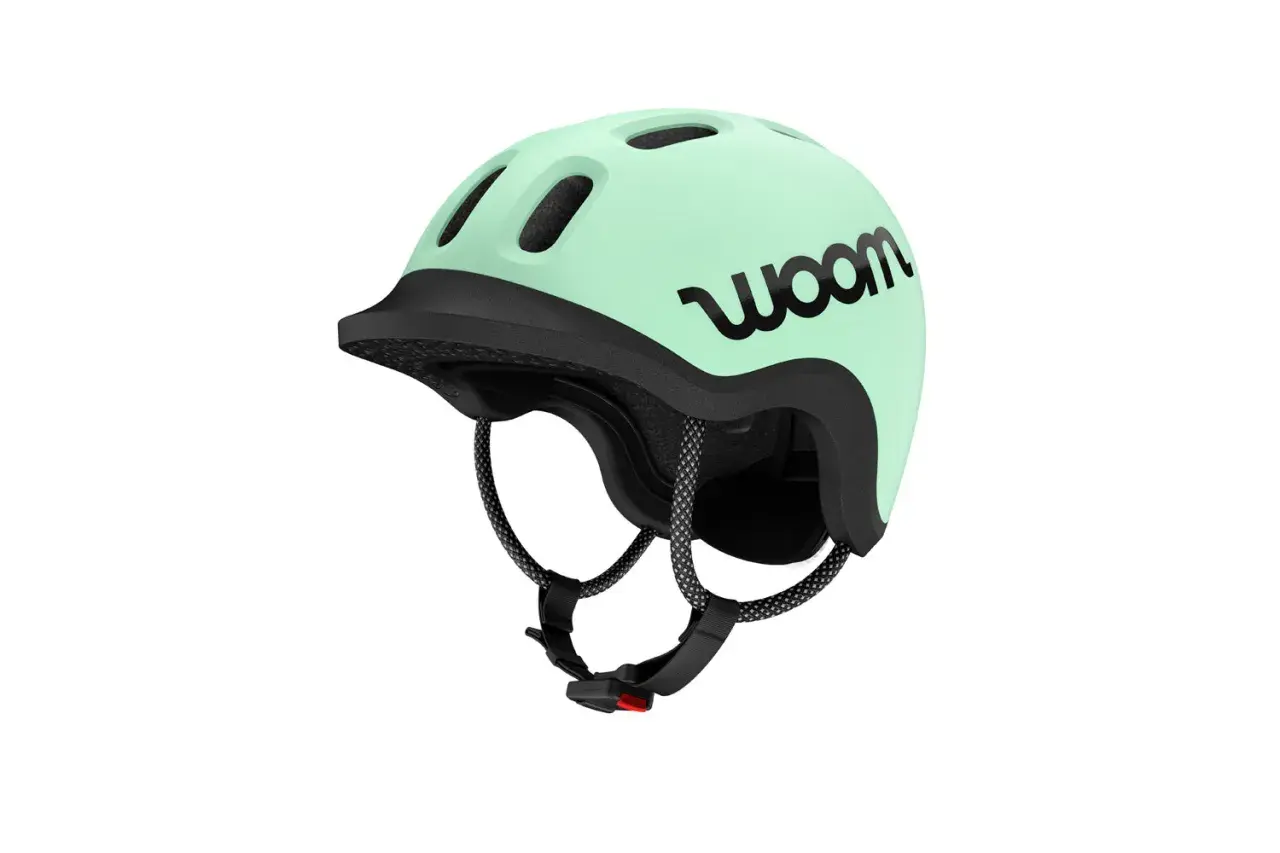 Miętowy kask rowerowy woom z czarnym logo. Idealny dla małego rowerzysty, zapewnia bezpieczeństwo i komfort.
