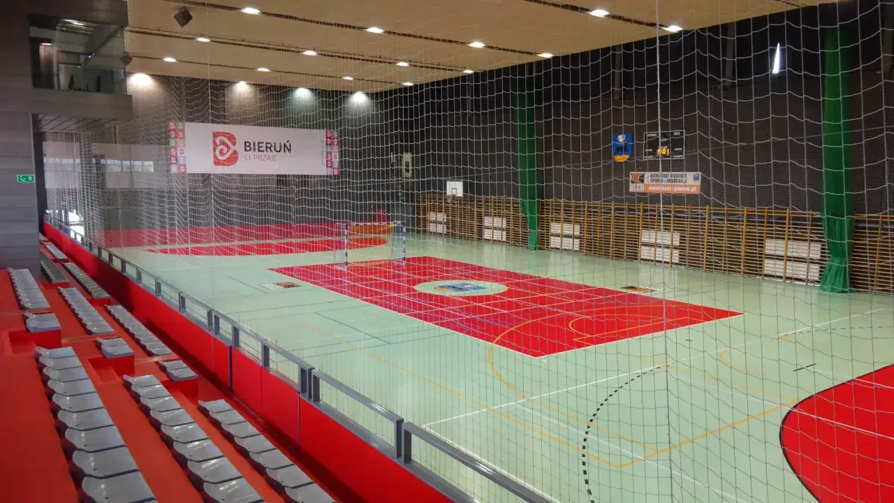 Hala sportowa w Bieruniu, gotowa na zawody. Widać boisko, trybuny i baner