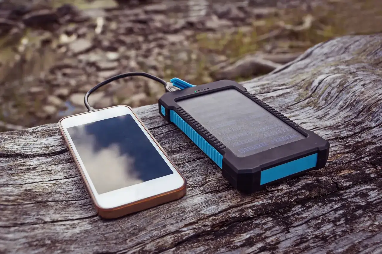 Smartfon podłączony do powerbanku solarnego, idealnego na rowerowe wyprawy.