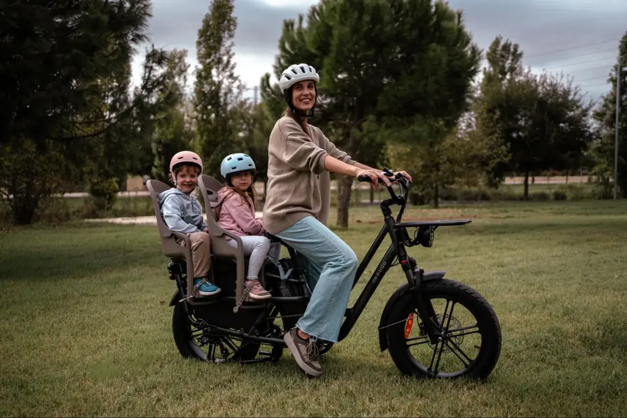Mama z dwójką dzieci na elektrycznym rowerze dla dzieci, cieszą się wspólną przejażdżką po parku.