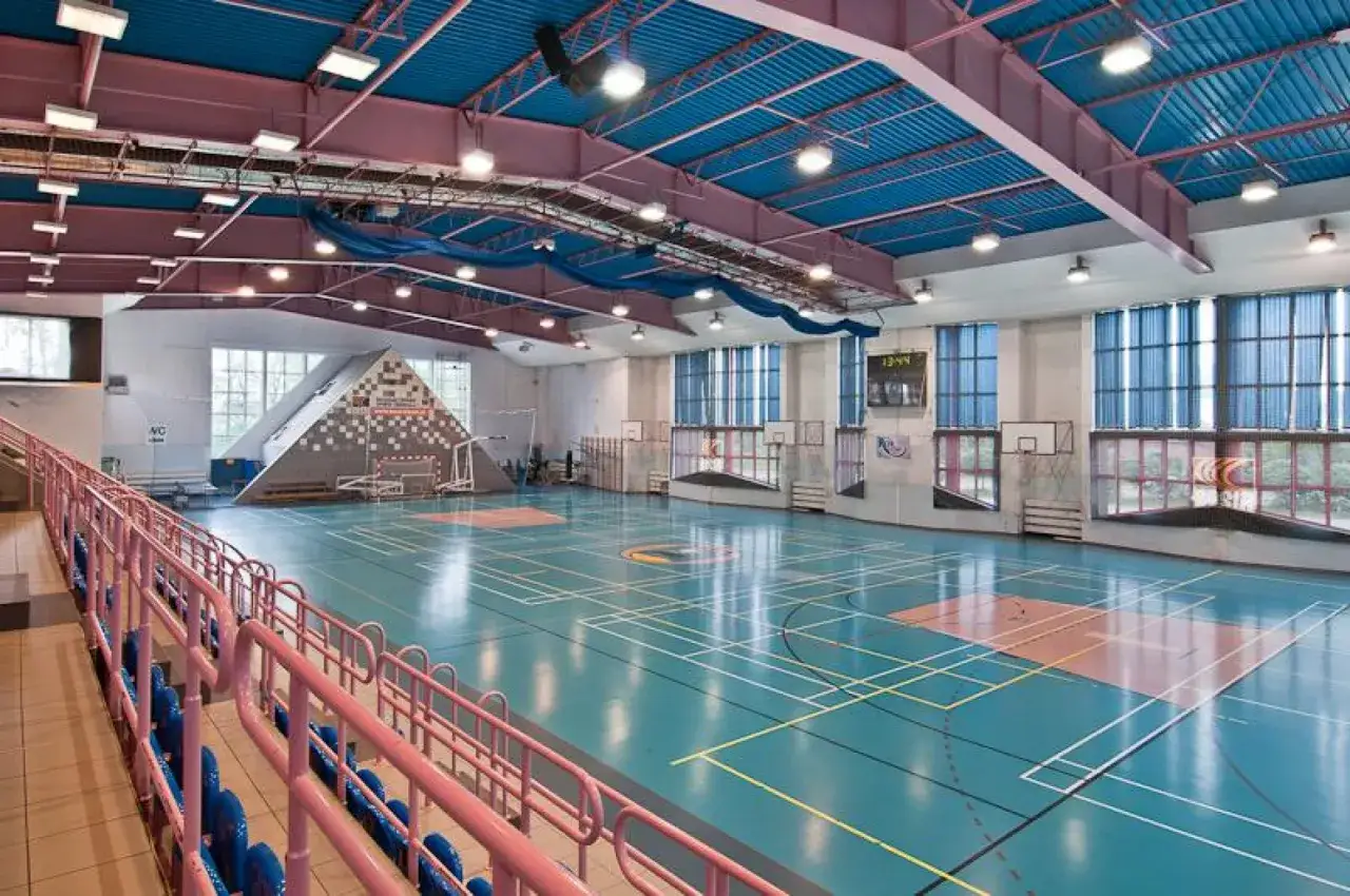 Hala sportowa w Bieruńskim Ośrodku Sportu i Rekreacji. Błękitna podłoga z liniami do gry, trybuny, tablica wyników.