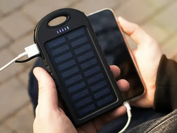 Ręce trzymające powerbank na rower z panelem słonecznym ładujący telefon. Idealny na wycieczki!
